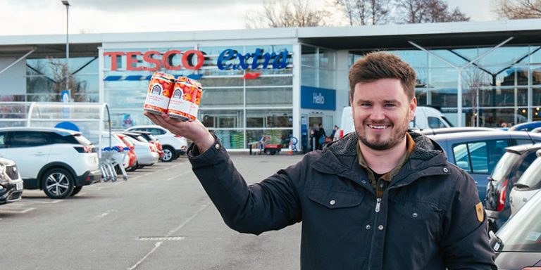 Man holding beer outside supermarket