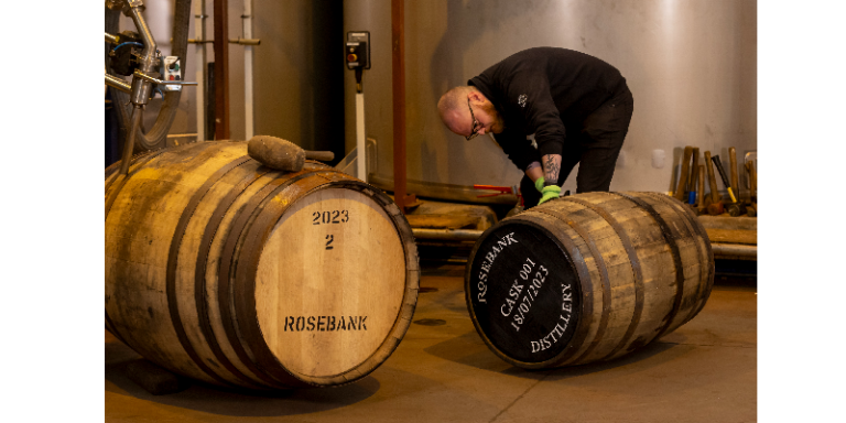 a man in a distillery with two casks