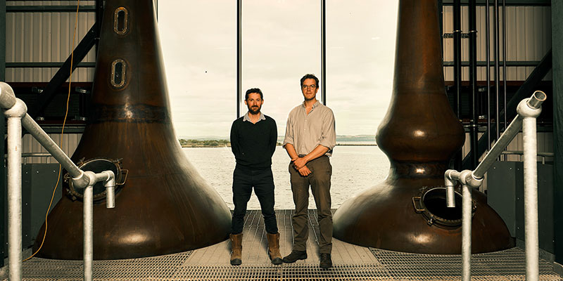 Two men beside whisky stills