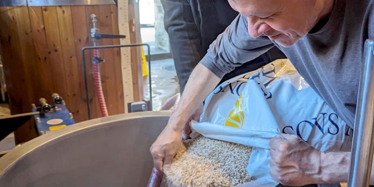 Man pouring grain into a vat.